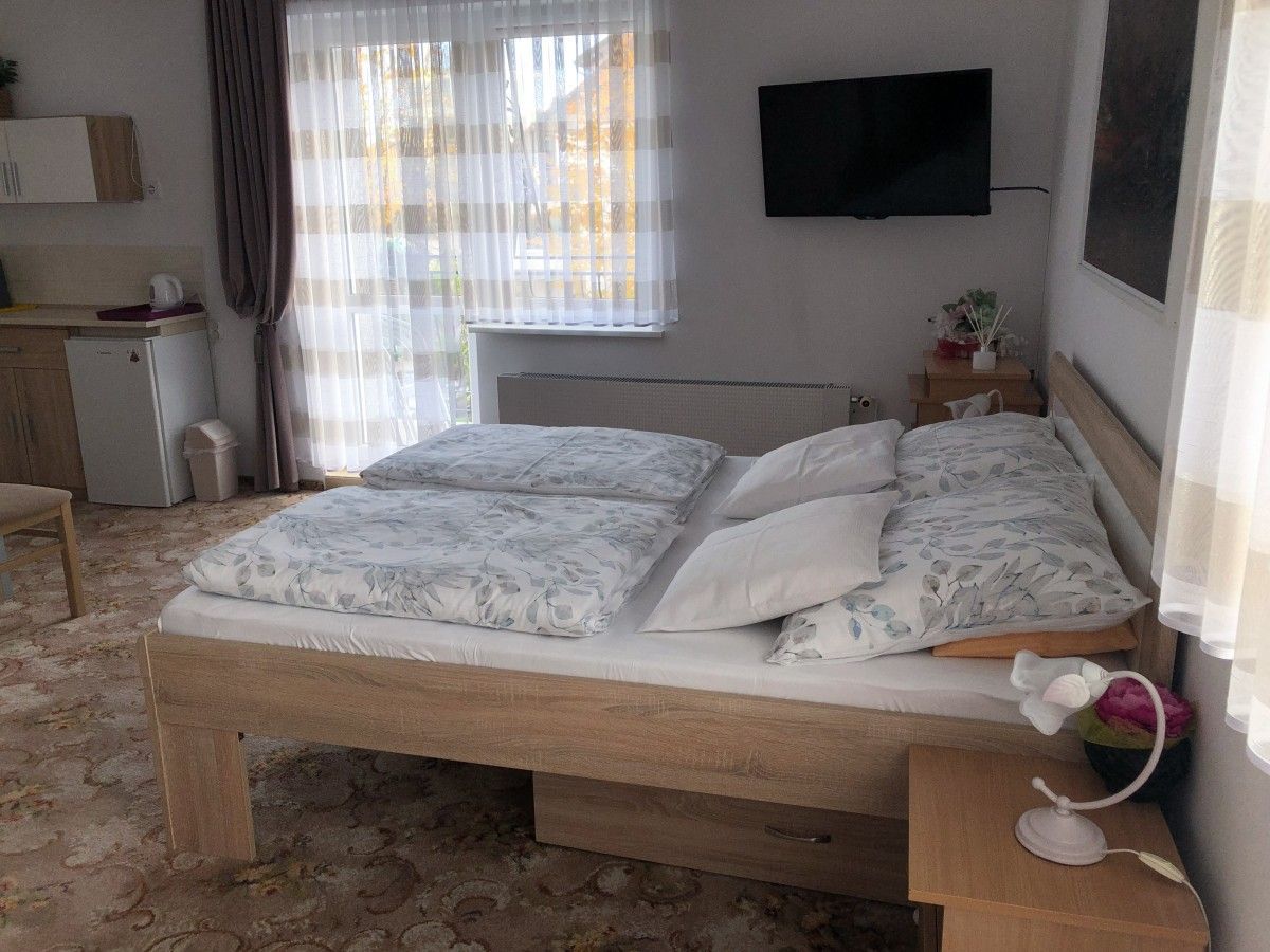 Podwójne łóżko, lodówka i wyjście na balkon